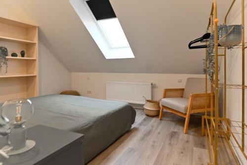 une chambre avec un lit, une chaise et une lucarne dans l'établissement Charming apartment in Miesenheim, à Andernach