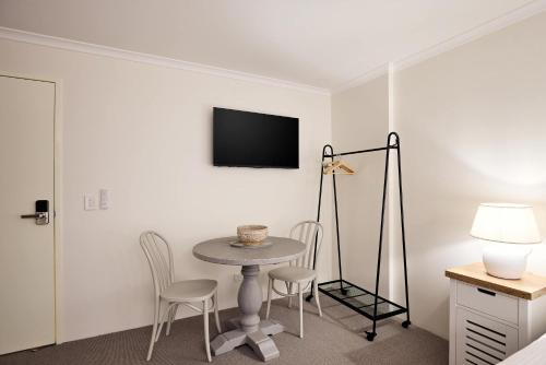 a room with a table and chairs and a tv at Queen Bed Studios with Sofa at Manly - 3min walk to Corso & Manly Beach in Sydney