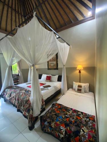 a bedroom with two beds with mosquito nets at Taruna Boutique Homestay & Spa in Pemuteran