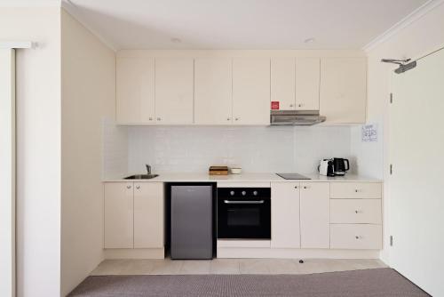 a kitchen with white cabinets and a black dishwasher at Queen Studios with Sofa Bed at Manly - 3min walk to Corso & Manly Beach in Sydney