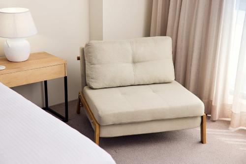 a chair in a bedroom with a desk and a lamp at Queen Studios with Sofa Bed at Manly - 3min walk to Corso & Manly Beach in Sydney