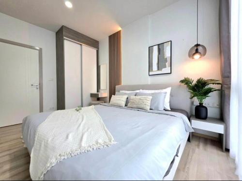 une chambre avec un grand lit blanc et une plante en pot dans l'établissement The Modern central Phuket base condo by luxStays, à Ban Rangeng