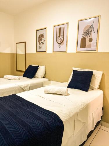 two beds in a room with pictures on the wall at Via Brasil Hotel in São Luís