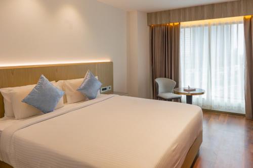 Un dormitorio con una gran cama blanca con almohadas azules. en Coral Reef Kakkanad, en Kochi
