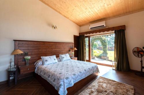 a bedroom with a bed and a large window at StayVista at Horizon 4BHK with Breakfast & Valley view in Kasauli