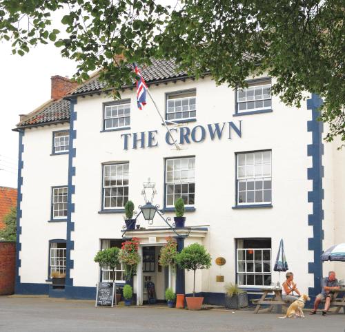 a white building with a sign that reads the crown inn at The Crown Hotel in Wells next the Sea