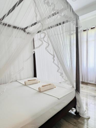 a bed with a canopy with two pillows on it at Aloe villa in Weligama