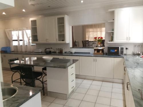 eine Küche mit weißen Schränken und einer schwarzen Arbeitsplatte in der Unterkunft Long Avenue Guest House in Johannesburg