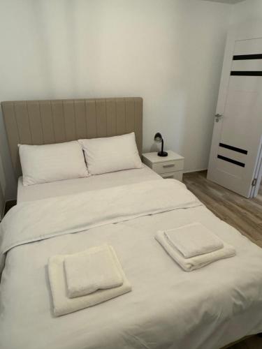 a white bed with two towels on top of it at illy apartament in Craiova
