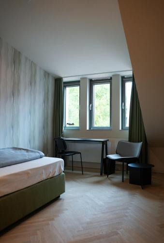Un dormitorio con cama, escritorio y ventanas en qnorke Hotel, en Berlín