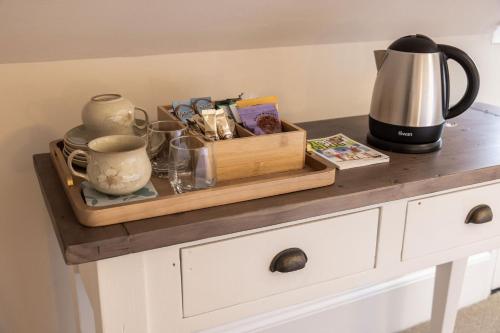 a counter with a tray with a coffee pot and a tea kettle at La Croix Guest House in Isle of Jersey