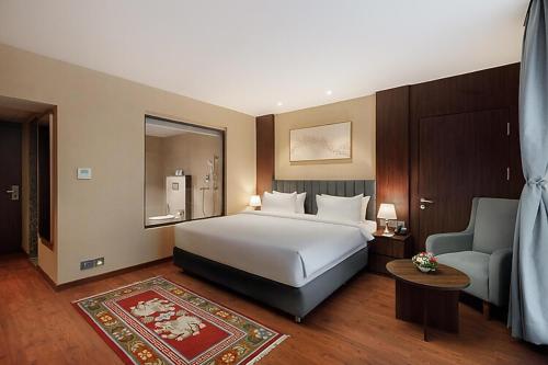 カトマンズにあるRoyal Tulip Kathmanduのベッドルーム(大型ベッド1台、ソファ、椅子付)