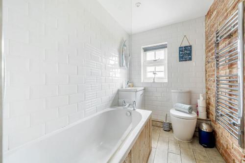 a white bathroom with a tub and a toilet at Sunset View in Thornham