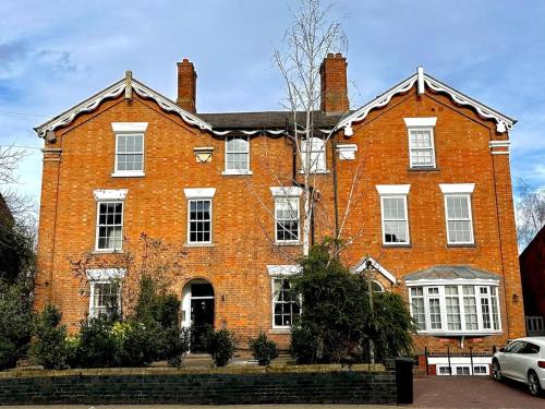 a large red brick building with a car parked in front at The Hideaway in Stratford-upon-Avon