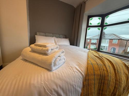 a bedroom with towels on a bed with a window at chesterton Grove in Manchester
