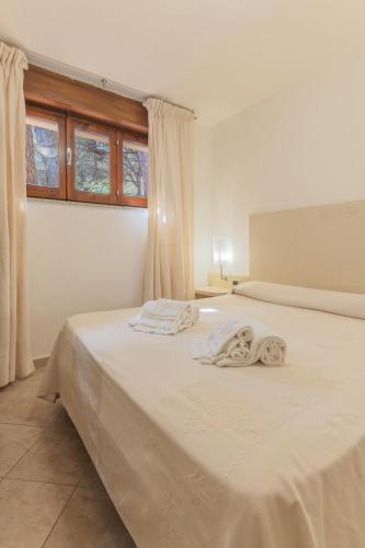 a bedroom with a white bed with towels on it at Club Hotel Residence Baiaverde in Valledoria