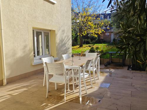 a wooden table and white chairs on a patio at Grande chambre cosy très proche centre ville in Le Mans