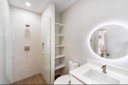 a white bathroom with a sink and a mirror at Oceanfront Residency luxury 2B2B ,1-6 person ,terrasse, beach access garden pool in Old Man Bay