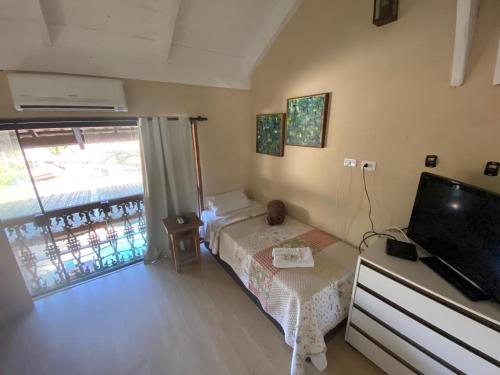 a small bedroom with a bed and a television at Pousada Reserva do Tombo Lounge Hostel in Guarujá