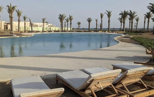 a swimming pool with lounge chairs and palm trees at Panoramic Seaview Somabay 1BR Apartment in Mesca in Hurghada