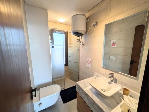 a bathroom with a sink and a toilet and a mirror at Panoramic Seaview Somabay 1BR Apartment in Mesca in Hurghada