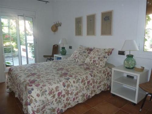 ein Schlafzimmer mit einem Bett mit geblümter Tagesdecke in der Unterkunft Casa de pueblo con jardín in Premiá de Mar