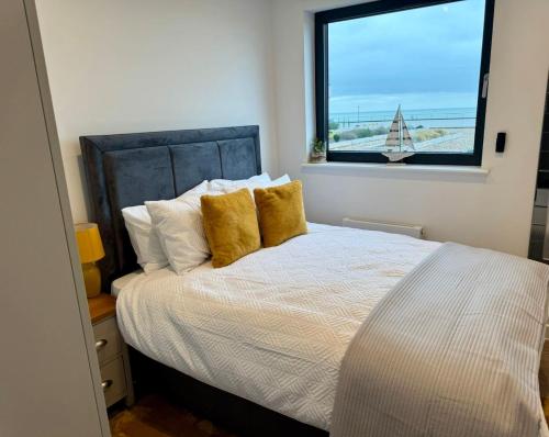 a bedroom with a bed with yellow pillows and a window at Harbour View - Steps From The Sea - Balcony - Parking in Ramsgate