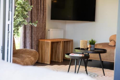 sala de estar con 2 mesas y TV en Vakantiepark de Witte Berg, en Ootmarsum
