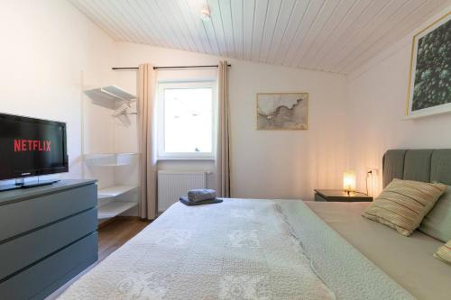 ein Schlafzimmer mit einem Bett, einem Fernseher und einem Fenster in der Unterkunft Luxus-Wellness-Haus am Waldsee in Rieden