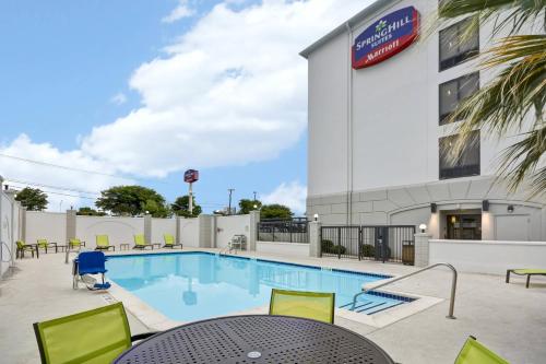 a pool with a table and chairs next to a building at SpringHill Suites by Marriott San Antonio Medical Center/Northwest in San Antonio