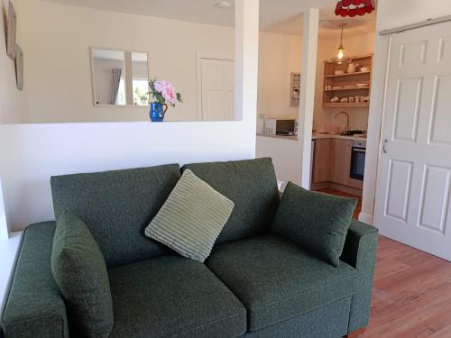 um sofá verde numa sala de estar com uma cozinha em The Free Range Room at The Cracked Hen em Gorey