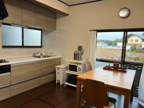 a kitchen with a table and a microwave and a window at Cai 芸術の家 in Tsukuba