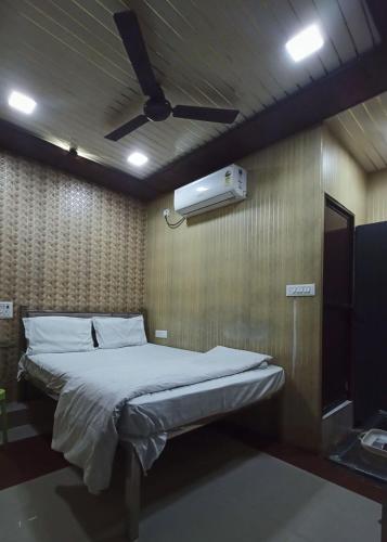a bedroom with a bed with a ceiling fan at Manya hotel and dormitory in Jhānsi