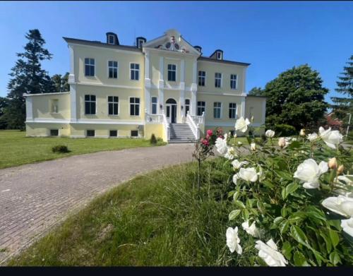 a large white house with flowers in front of it at Schloss Schmuggerow in Schmuggerow