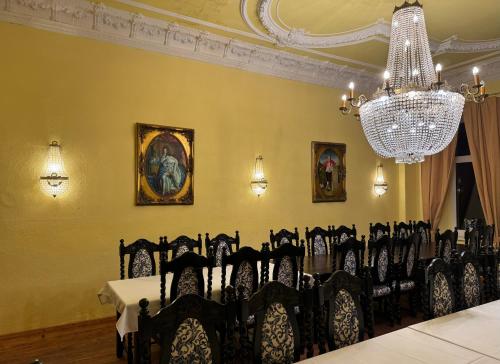 a dining room with black chairs and a chandelier at Schloss Schmuggerow in Schmuggerow
