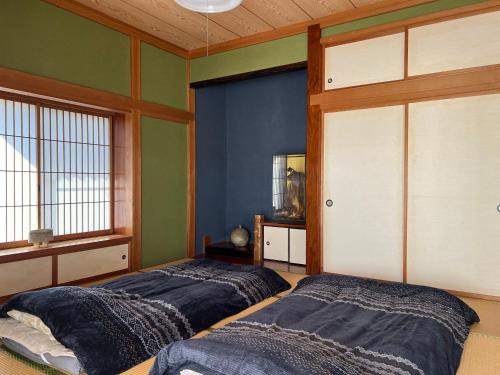 two beds in a room with green walls at Cai 芸術の家 in Tsukuba