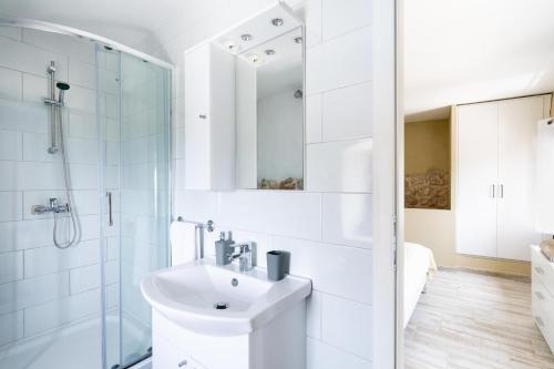 een witte badkamer met een wastafel en een douche bij Duka by Vintage Travel in Butkovine
