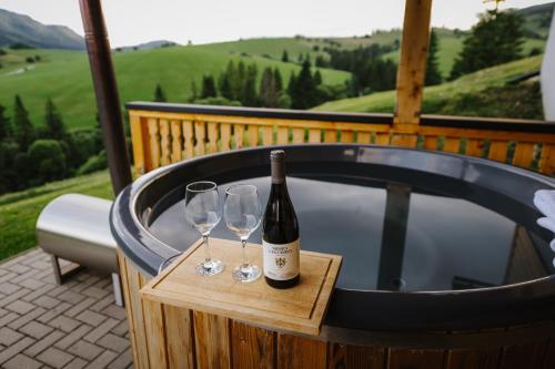 a bottle of wine and two wine glasses sitting on a hot tub at Chaty v Ráztoke in Veľké Borové