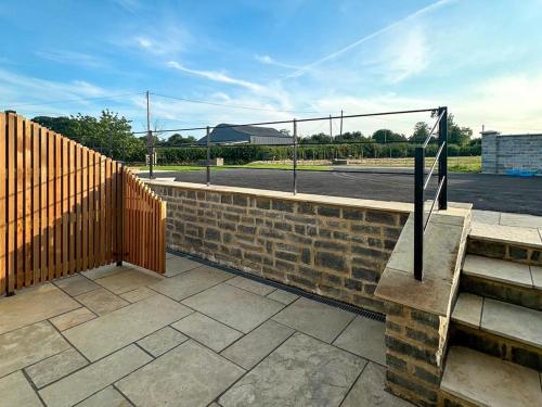 a brick wall with a wooden fence next to a street at The Spud Shed - Uk47419 in Curry Mallet