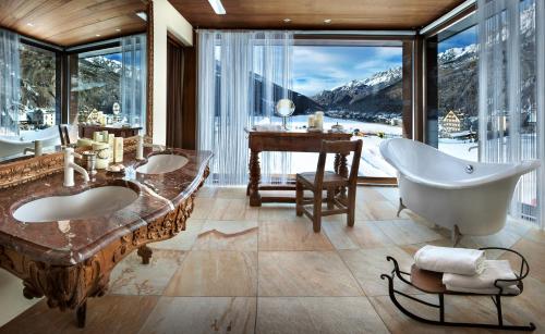 a bathroom with two sinks and a tub and a piano at Bellevue Hotel & SPA in Cogne