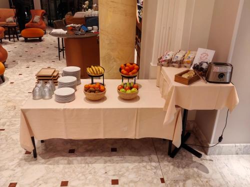 a table with bowls of fruit and plates on it at Hôtel de la Paix Lausanne in Lausanne