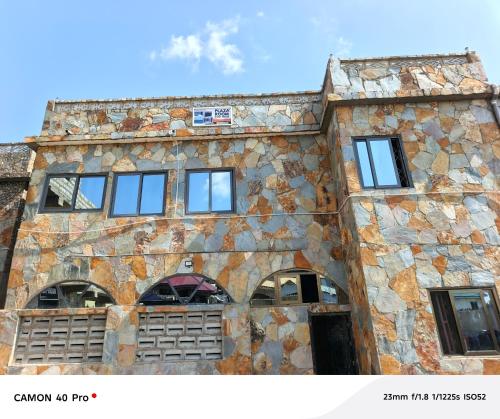 - un bâtiment en pierre avec des fenêtres sur le côté dans l'établissement Plaza Room Guest House, à Abrekuma