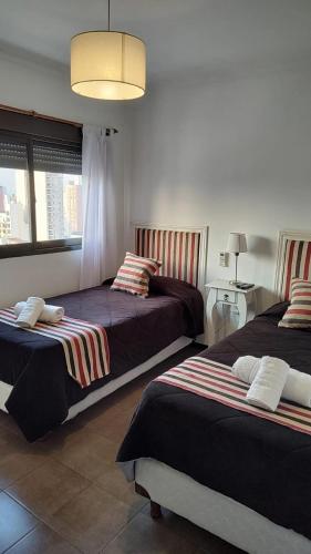 a bedroom with two beds and a table with a lamp at Apartamento 4 de Enero in Santa Fe