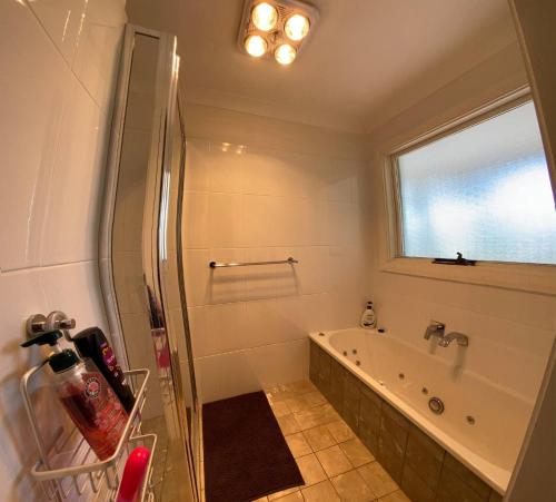 a bathroom with a shower and a tub and a window at Govetts Leap lookout cottage with sauna in Blackheath