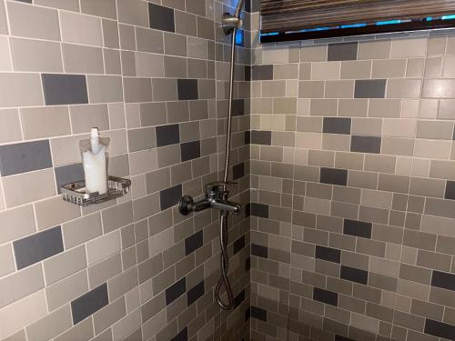 a shower in a bathroom with gray and black tiles at Nabs lodge in Kumasi