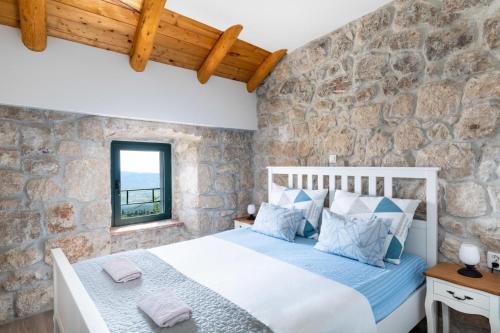 a bedroom with a bed and a stone wall at Luciana by Vintage Travel in Mihanići