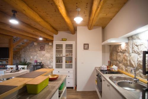 a kitchen with wooden ceilings and a stone wall at Luciana by Vintage Travel in Mihanići