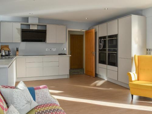 eine Küche mit weißen Schränken und einem Sofa in einem Zimmer in der Unterkunft Pines Cottage - Uk42110 in St Margarets at Cliff