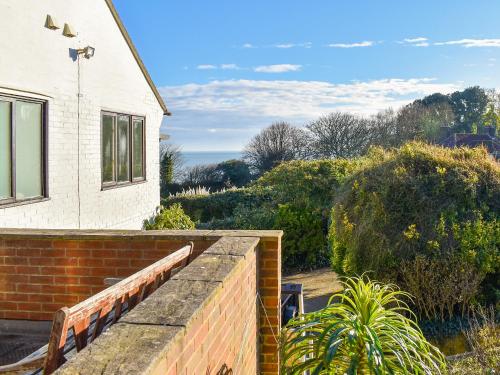 a house with a brick retaining wall next to a building at Pines Cottage - Uk42110 in St Margarets at Cliff