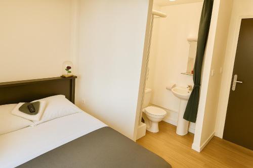 a small bathroom with a bed and a toilet at Hôtel Le Paris Brest in Lens